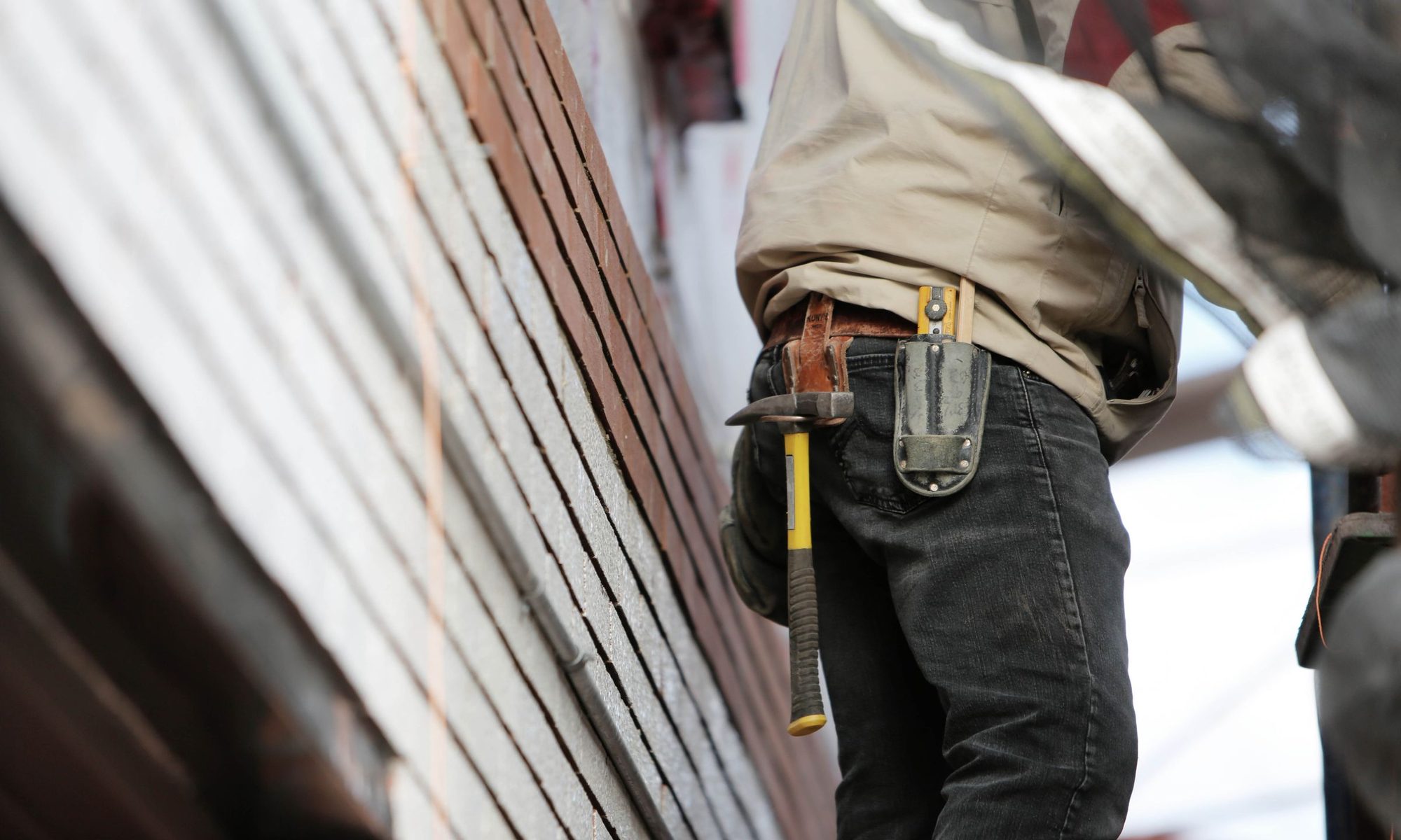 Handyman with a tool belt working on a home exterior