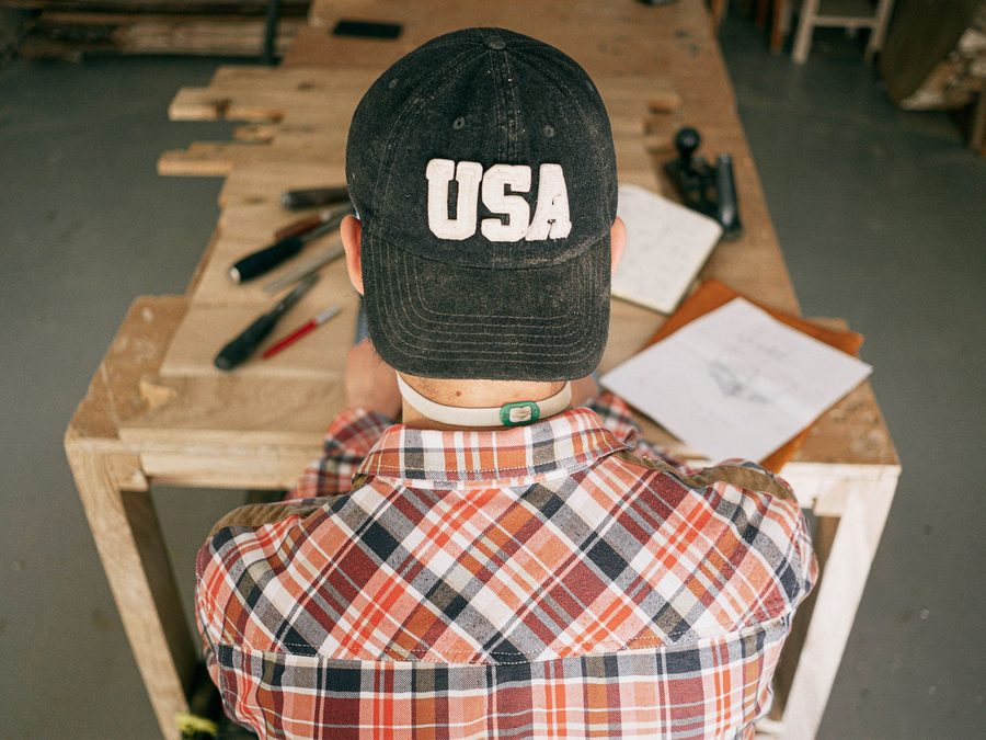 Carpenter at a workbench shaping a piece of lumber
