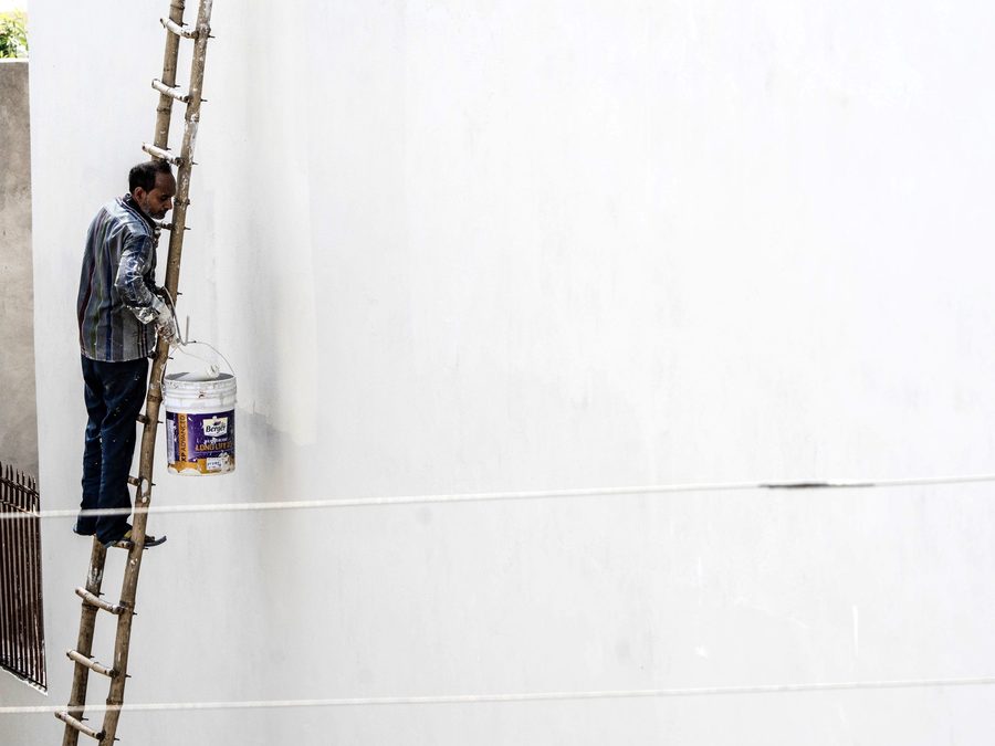 Painter on a ladder applying a fresh coat to a wall